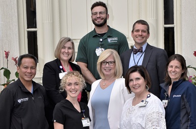 Eight members of Pennsylvania Hospital’s Diversity, Equity, and Inclusion Committee, with Theresa in the center of the group, stand on steps outside of the hospital 